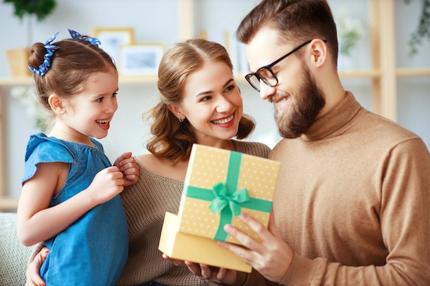 Feliz día del padre, familia, mamá e hija felicitan a papá y le dan un regalo.