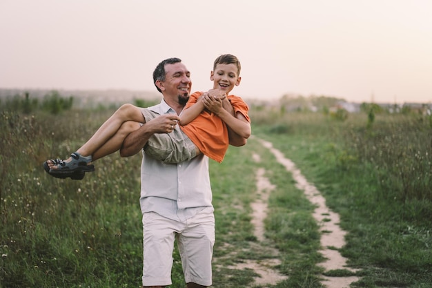 Feliz día del padre Padre con hijo caminando en el campo Papá abraza al niño El concepto de las relaciones del día del padre con los niños cuidan y aman