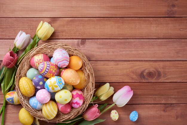 Feliz día de Pascua huevos en cesta y flor sobre fondo de madera con espacio de copia