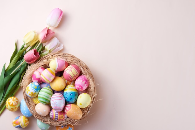 Feliz día de Pascua huevos coloridos en nido y flor sobre fondo de papel con espacio de copia