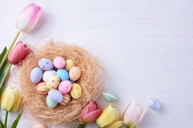 Feliz día de Pascua huevos en nido y flor sobre fondo de madera con espacio de copia