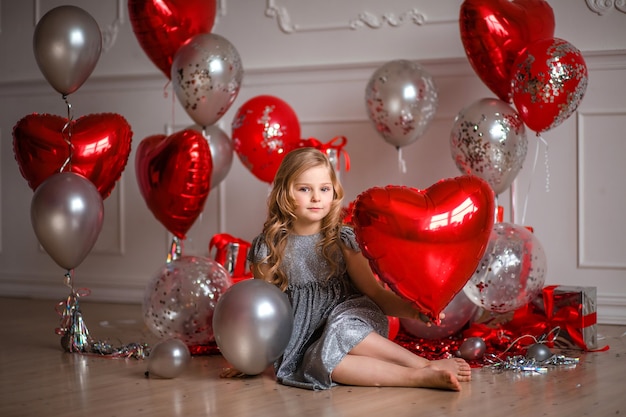 ¡Feliz día de San Valentín! linda chica en vestido rojo con globos y confeti