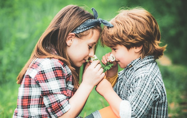 Feliz día de San Valentín, los niños hermosos disfrutan soplando el diente de león en el parque de la primavera