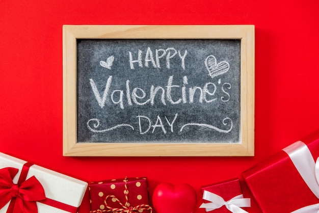 Feliz día de San Valentín texto escrito a mano en la pizarra con caja de regalo