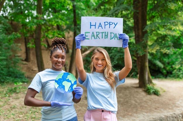 Feliz Día de la Tierra Gente limpiando basura en el césped Grupo de jóvenes internacionales construyendo equipo al aire libre en el parque Voluntarios juntos recogen basura en el parque