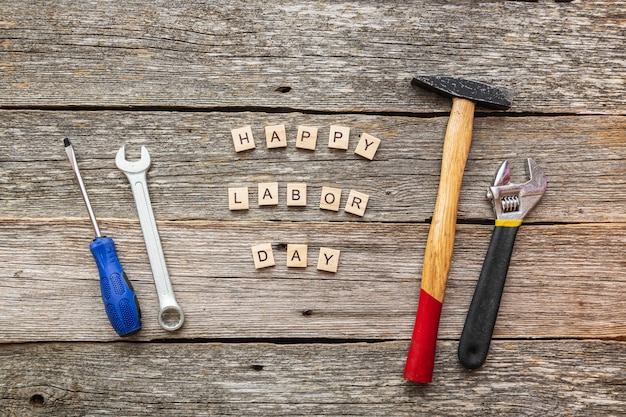 Feliz día del trabajo en bloques de madera y herramientas de construcción en la vista superior de fondo de madera