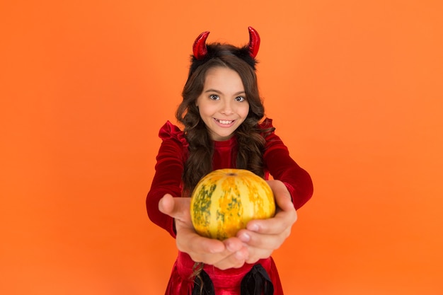 Feliz diablo de halloween. niño adolescente con cuernos de diablillo. niño alegre lleva calabaza. haciendo jack o lantern. fiesta de disfraces de carnaval. truco o trato. celebrar las fiestas. infancia.