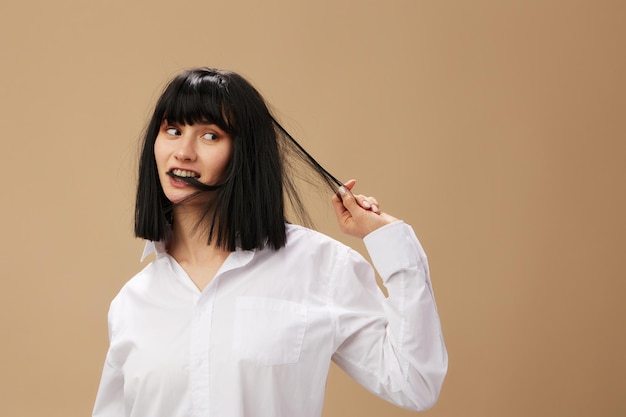 Foto feliz disfrutado lindo elegante adorable dama morena en camisa blanca coqueteando sonriendo posando aislado en fondo de estudio beige pastel espacio de copia oferta de pancarta pulpa concepto de ficción cine de moda