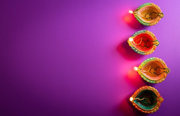 Feliz Diwali Clay Diya lámparas encendidas durante el festival hindú de luces Dipavali celebración Colorida lámpara de aceite tradicional diya sobre fondo púrpura