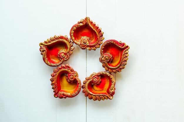 Feliz Diwali, lâmpadas de Clay Diya iluminadas durante Dipavali, celebração hindu do festival de luzes. Diya tradicional colorido da lâmpada de óleo no branco de madeira