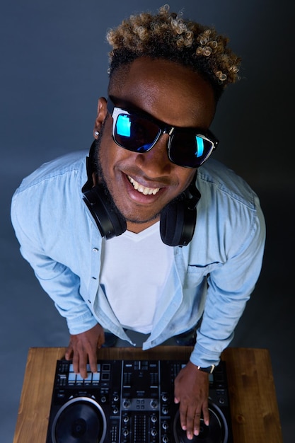 Feliz DJ afroamericano con peinado afro toca música con gafas de sol