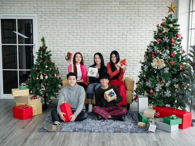 Feliz do grupo de jovens asiáticos com presentes em casa para comemorar o festival de natal. grupo de amigos se vestindo para a festa de natal juntos. comemorando o ano novo. feliz natal e boas festas.