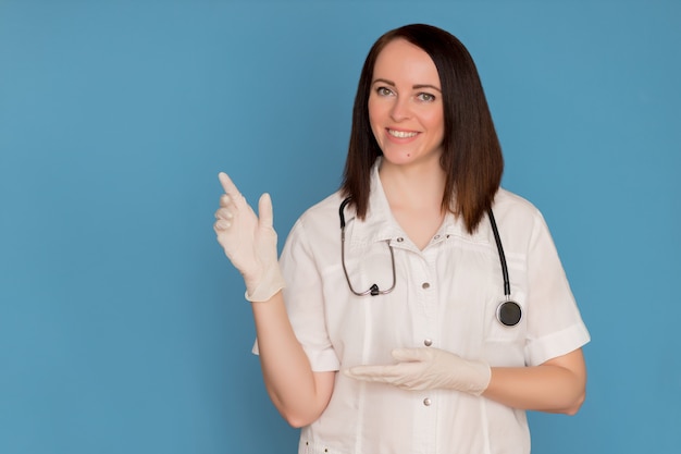 Feliz doctora en guantes médicos con un estetoscopio apuntando para copiar espacio