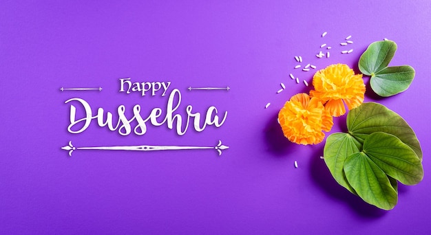 Feliz Dussehra. Flores amarillas, hojas verdes y arroz sobre fondo violeta pastel