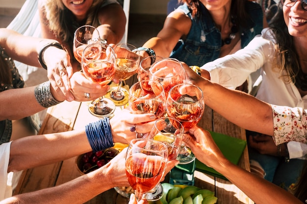 Feliz e alegre grupo de jovens amigas, torcendo e brindando, comemorando com vinho tinto