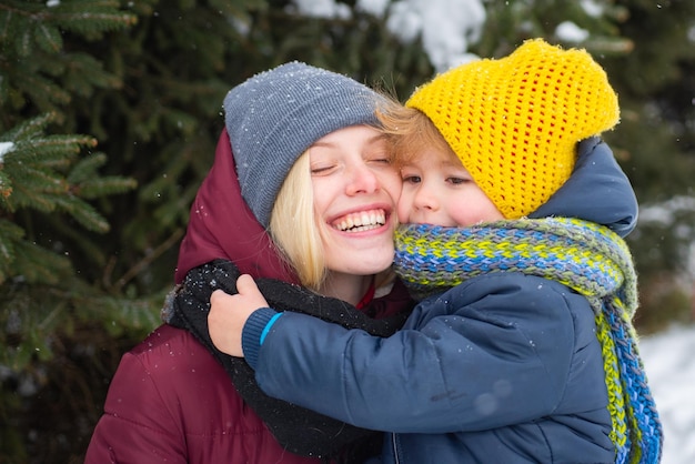 Feliz e alegre mãe sorridente com seu filho fofo no fundo nevado caminho florestal coberto de neve inverno h