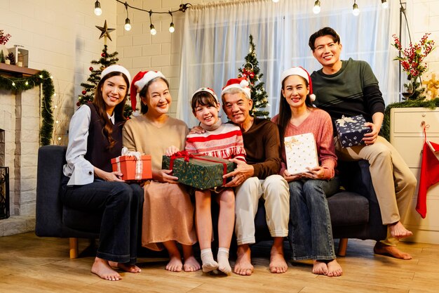 Feliz e alegre reunião de família asiática vestindo chapéus de Papai Noel falando e sorrindo trocando presentes