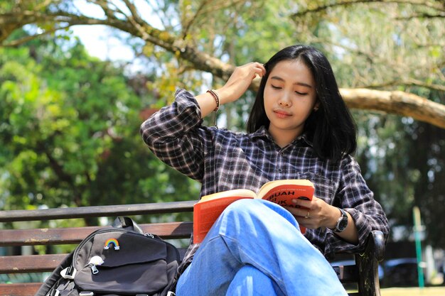 feliz e atenta jovem estudante universitária asiática lendo um livro no conceito de educação do parque