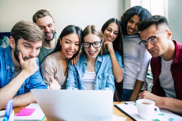 Feliz e bem sucedido grupo moderno de equipe de inicialização de negócios está olhando no monitor do laptop depois de concluído o grande projeto. alunos engraçados