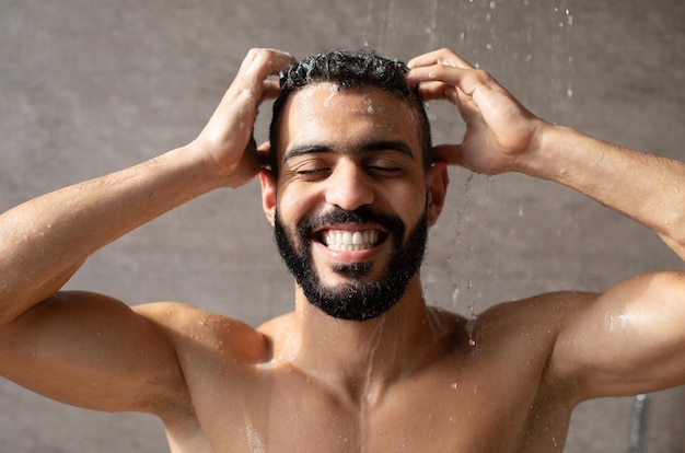 Feliz e bonito jovem modelo masculino árabe tomando banho quente