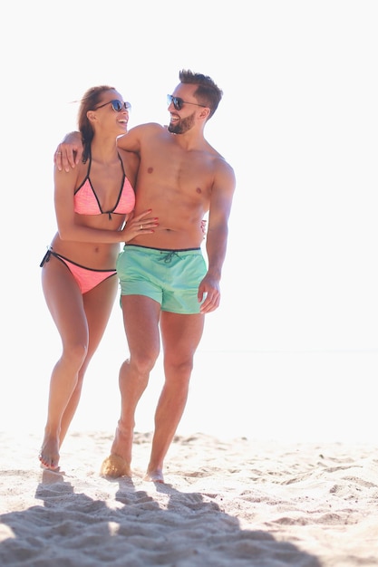 Feliz e divertido casal de férias na praia caminhando juntos rindo se divertindo no destino de viagem