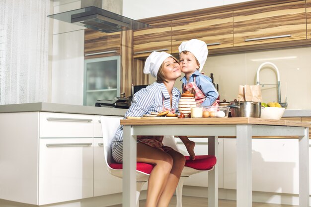 Feliz e linda mãe e filho família reunidos na cozinha cozinhando