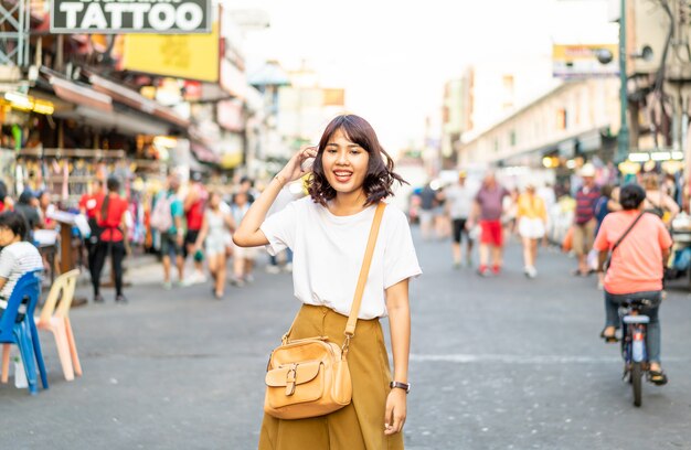 Feliz e linda mulher asiática viajando na Khao Sarn Road, Tailândia