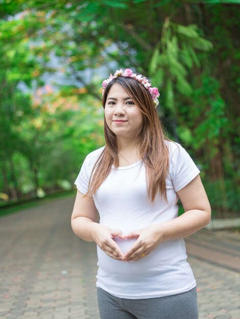 Feliz e orgulhosa mulher grávida segurando a barriga em um parque