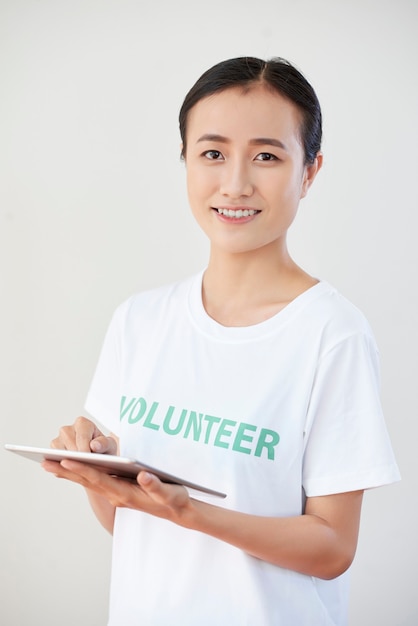 Feliz e sorridente jovem voluntário membro da organização preenchendo documento ou questionário no computador tablet