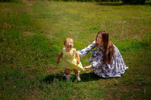Feliz elegante jovem mãe brinca com sua filha no jardim verde