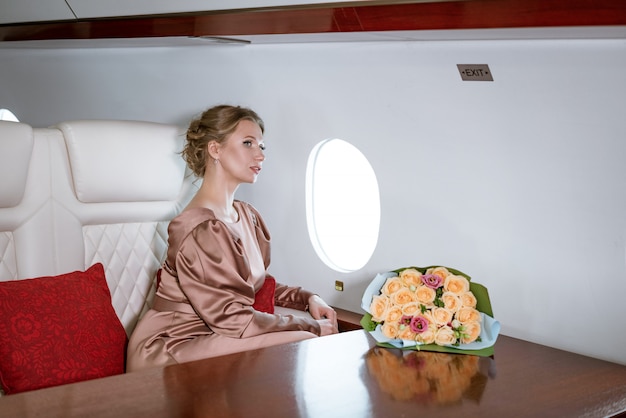 Feliz elegante mujer sentada en un avión privado a la ventana