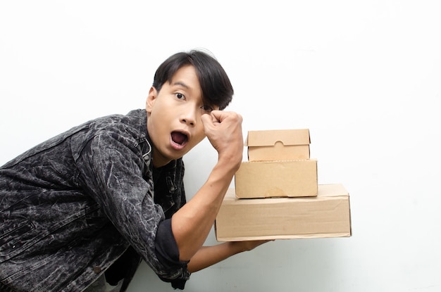 Feliz em êxtase jovem asiático segurando pacote conceito de serviço de entrega de remessa de caixa de encomendas.