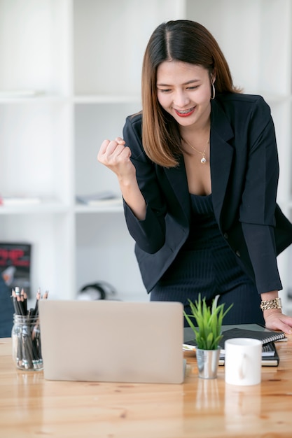 Feliz emocionada exitosa empresaria triunfando mientras trabajaba en la oficina moderna.