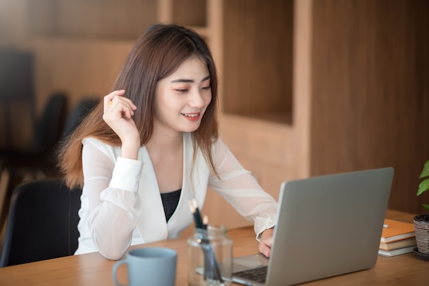 Feliz emocionada joven empresaria asiática exitosa trabajando en la oficina