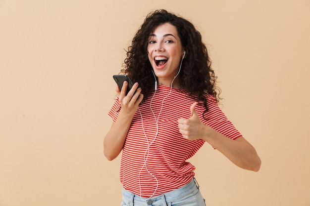 Feliz emocionada joven mujer rizada escuchando música