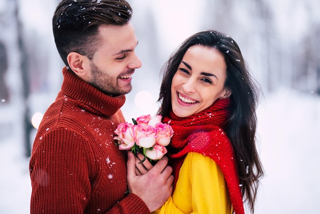 Feliz y emocionada pareja de enamorados se divierten, bailan y se abrazan al aire libre en el parque de la ciudad de invierno mientras celebran el día de San Valentín