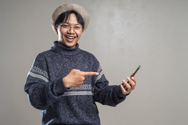Feliz emocionado joven asiático shock apuntando smartphone