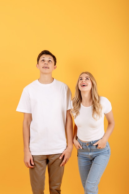 Feliz emocional homem e mulher olhando para cima para o espaço vazio, fundo laranja studio