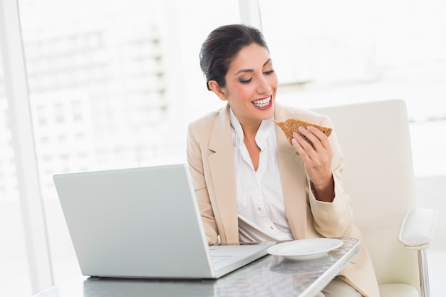 Feliz empresaria almorzando mientras ella está trabajando