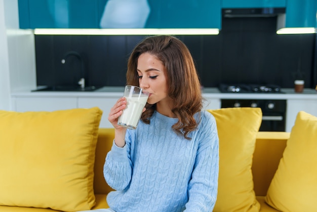 Feliz empresaria bebiendo una taza de café en su sofá