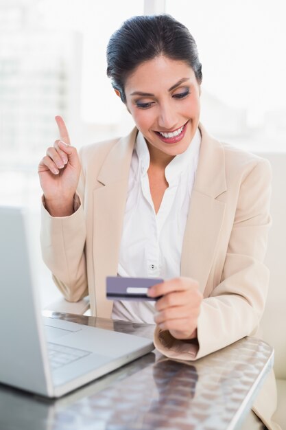 Foto feliz empresaria de compras en línea con la computadora portátil y apuntando