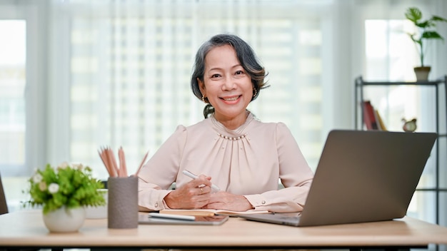 Feliz empresária dos anos 60 sentada em sua mesa sorrindo e olhando para a câmera