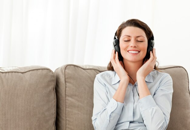 Feliz empresaria escuchando música con auriculares