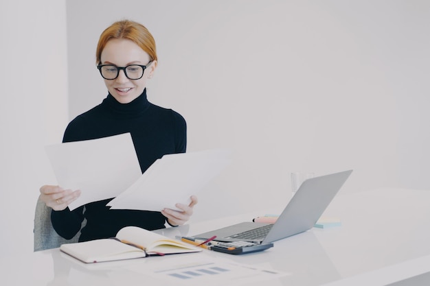 Feliz empresária europeia está fazendo papelada e sorrindo Conceito de sucesso nos negócios