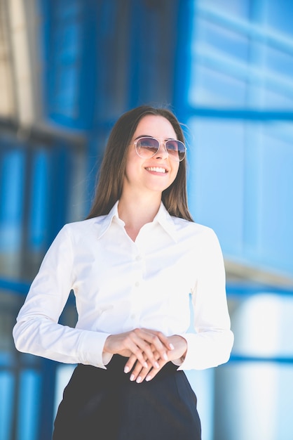 Foto la feliz empresaria en gafas de sol de pie en el fondo del edificio