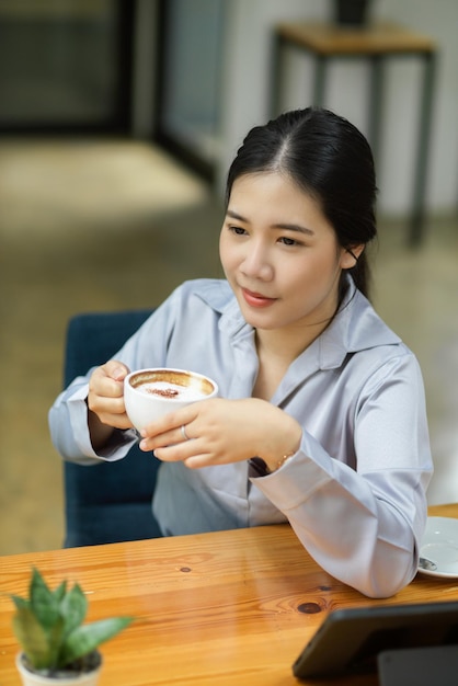 Feliz empresaria joven disfrutando de su café de la tarde en su escritorio en la oficina.