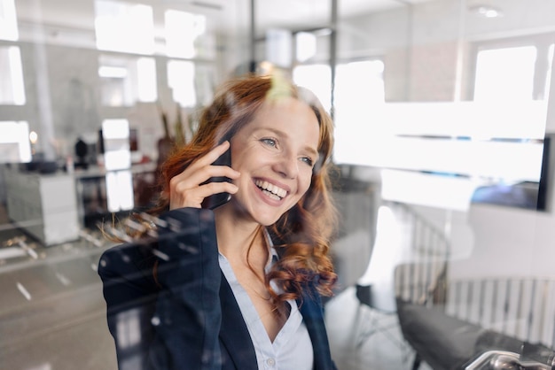 Feliz empresária ruiva ao telefone no escritório