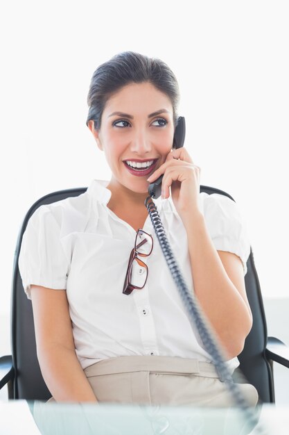 Feliz empresária sentada em sua mesa no telefone