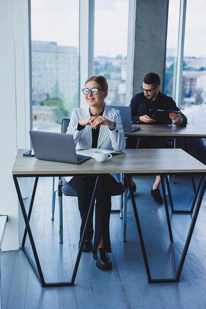 Foto feliz empresária trabalhando no laptop conceito de cooperação empresarial e trabalho em equipe jovens à mesa no escritório pessoas modernas de sucesso