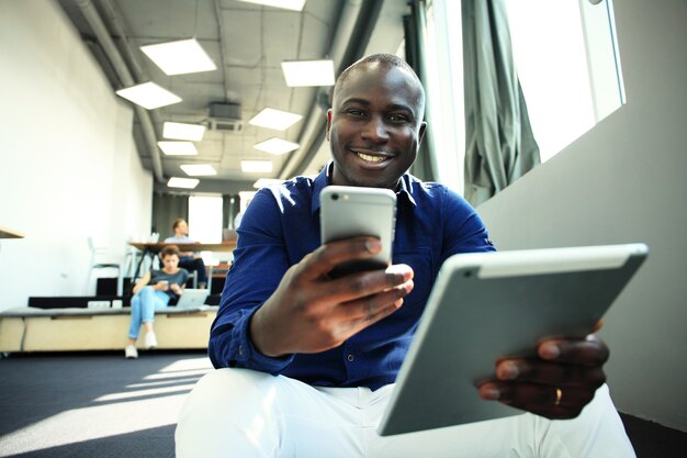 Feliz empresário afro-americano usando computador tablet.